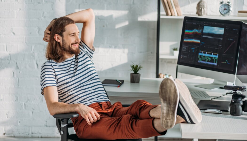 happy filmmaker resting near computer monitors in studio